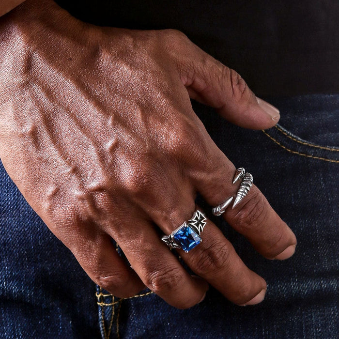 A man's hand wearing the blue sapphire Iron Cross ring and a claw ring.