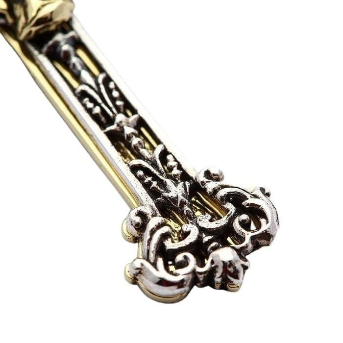 Macro view of the lower cross arm, highlighting the ornate sterling silver scrollwork layered over a smooth brass base.