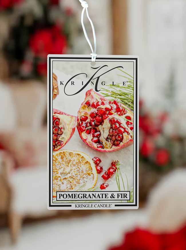 Kringle Candle Pomegranate & Fir air freshener tag with a blurred festive background.