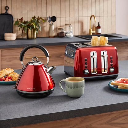 Red kettle and toaster on a kitchen counter with a cup of coffee and breakfast items.