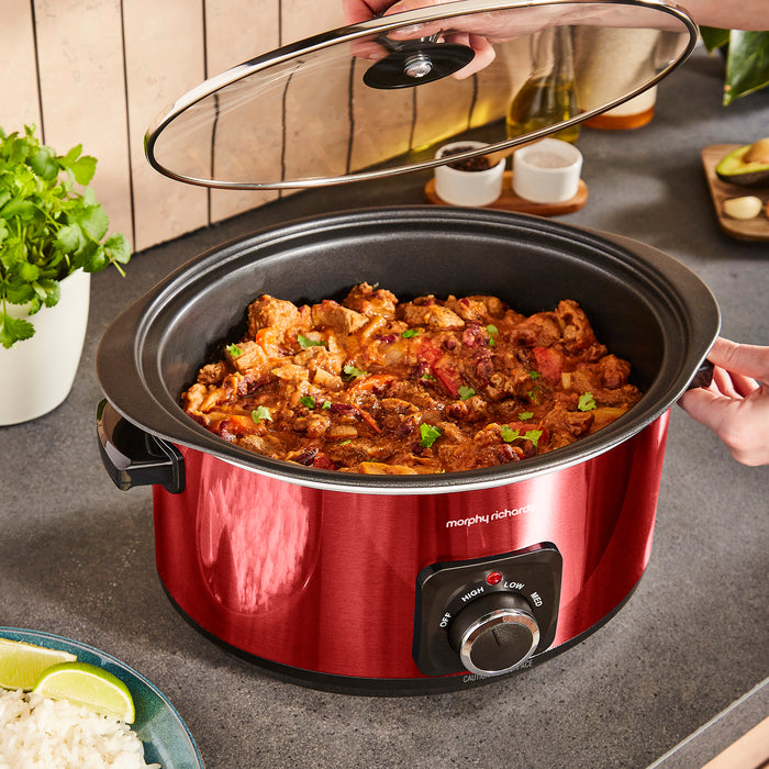 Red slow cooker with food inside on a kitchen counter