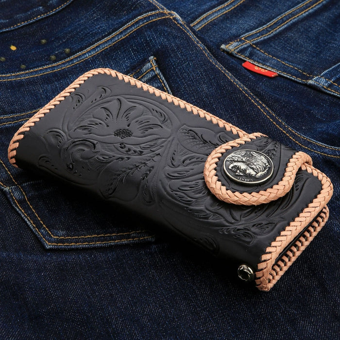 An angled view of the black leather long wallet showcasing the detailed whipstitch edge and floral carvings.