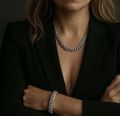 Kvinna som bär ett brett kedjehalsband med matchande armband i silver. Kedjemodell: Pansarkedja.