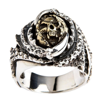 A front view of the two-tone claw devil ring, showing a brass skull held by a textured sterling silver claw.