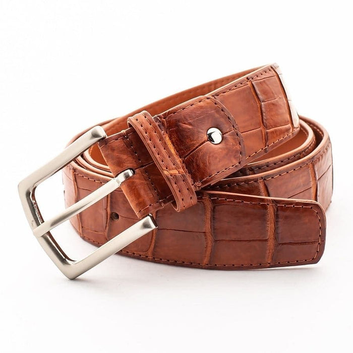 Genuine crocodile leather belt in cognac brown coiled to show texture and silver buckle