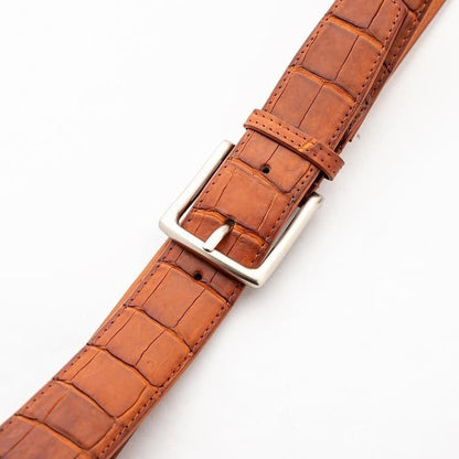 Crocodile leather dress belt buckle closeup showing brushed silver hardware and belt holes