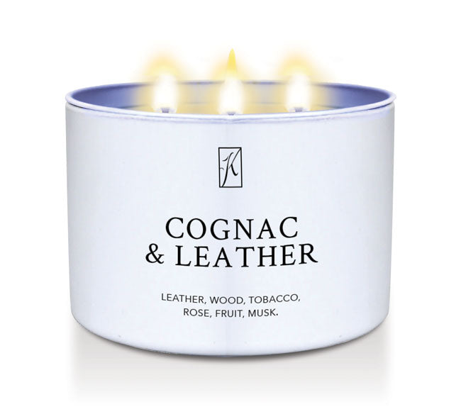 Candle in a white tin container labeled 'Cognac & Leather' with flames on a white background