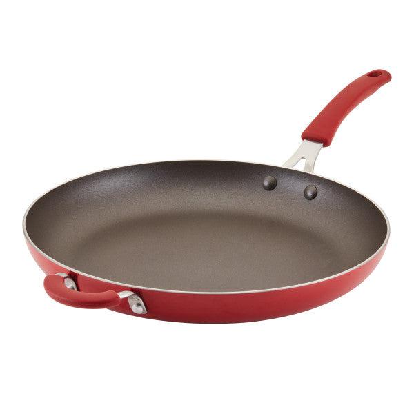 The Cook + Create Nonstick Frying Pan is a high-performance red frying pan made from durable aluminum, equipped with a long handle and a handy helper handle for versatile cooking.