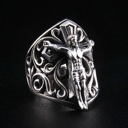Angled view showing raised crucifix figure and intricate scroll design on silver ring
