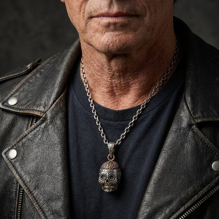 Man in a black leather jacket wearing a silver Day of the Dead skull pendant with copper details on a chain necklace.