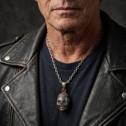Man in a black leather jacket wearing a silver Day of the Dead skull pendant with copper details on a chain necklace.