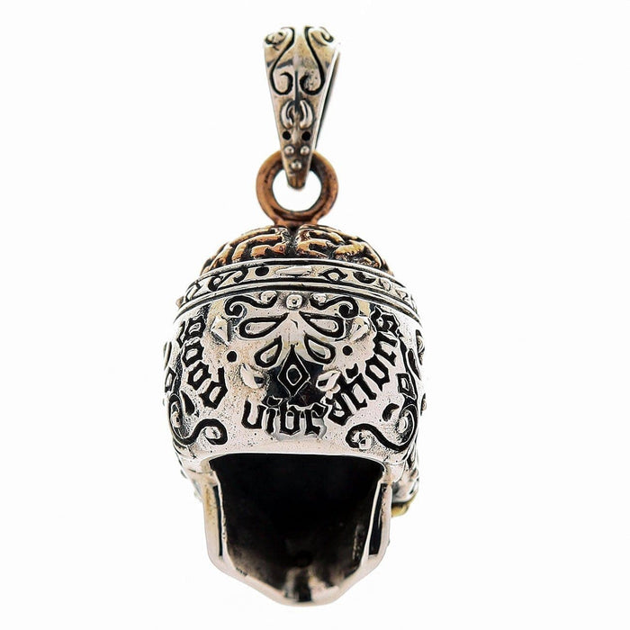 Engraved scrollwork and the words good vibrations cover the skull, with a brass crown and copper jump ring.
