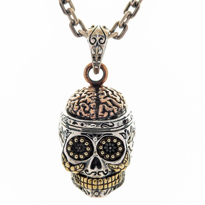A detailed Mexican skull pendant with intricate engravings, shown hanging from a sterling silver chain.