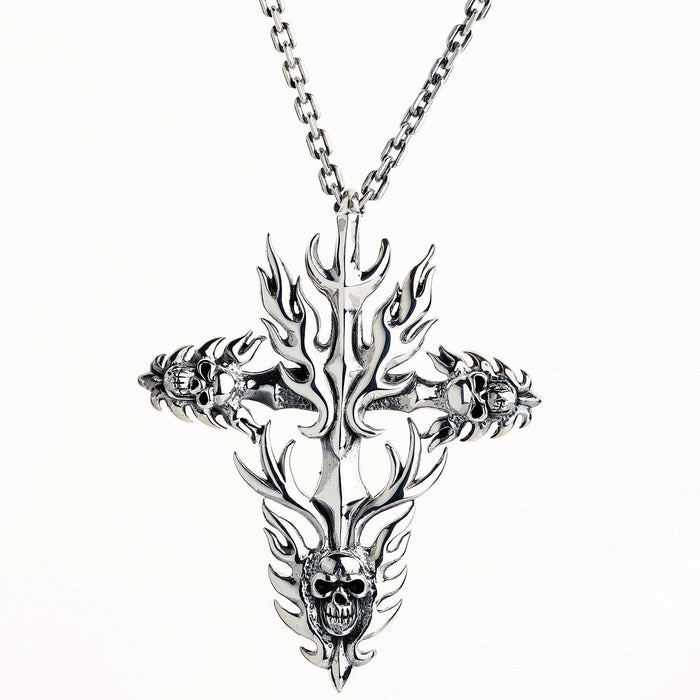 Polished silver flame cross pendant with skull accents on the lower arms, suspended from a classic link chain.