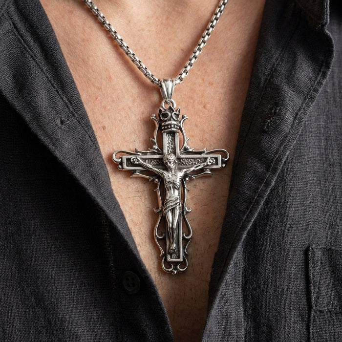 Man wearing gothic sterling silver crucifix pendant on box chain necklace with open collar dark shirt