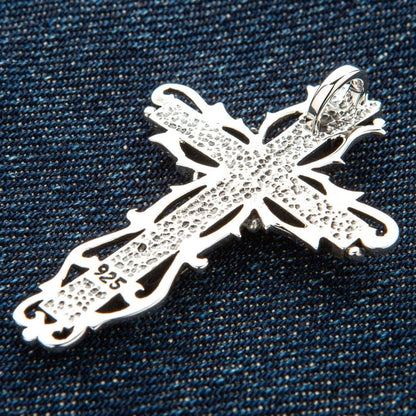 Back of sterling silver gothic crucifix pendant showing 925 hallmark stamp and hammered texture on denim