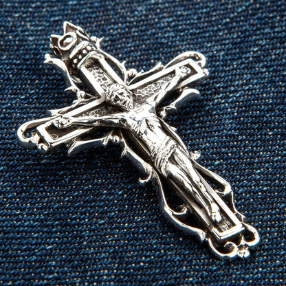 Angled detail shot of gothic sterling silver crucifix pendant highlighting thorny vine accents and crown motif