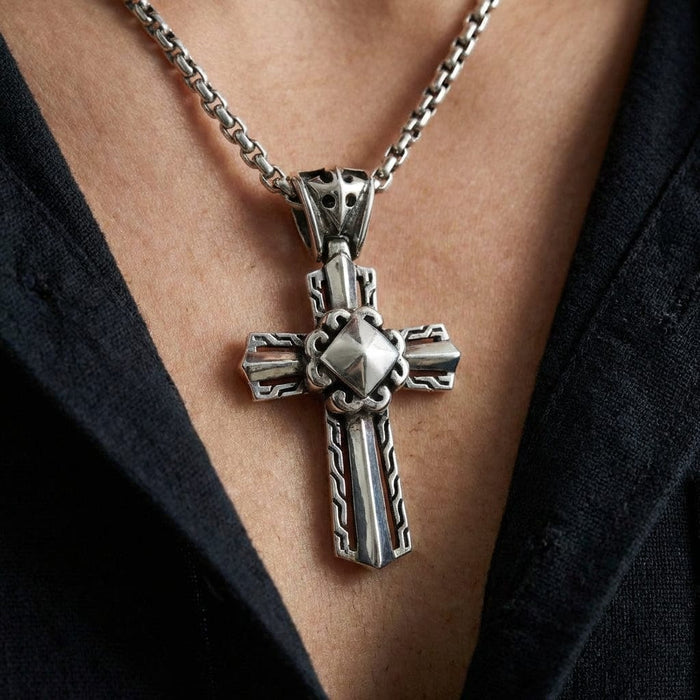 Sterling silver men's knight cross pendant with intricate Celtic knot patterns and pyramid center detail, worn on a box chain necklace against a dark shirt background