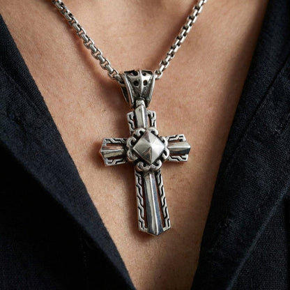 Sterling silver men's knight cross pendant with intricate Celtic knot patterns and pyramid center detail, worn on a box chain necklace against a dark shirt background