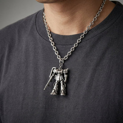 A man wearing a detailed silver Gundam Zaku robot pendant on a thick silver chain necklace over a dark grey t-shirt.