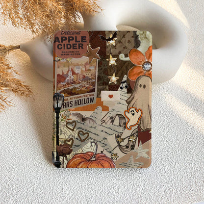 Notebook with Halloween-themed design featuring pumpkins, ghosts, and autumn elements on a textured surface.