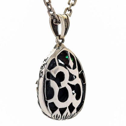 An Om symbol is cut through the back plate, showing the dark stone behind it inside an engraved oval frame.