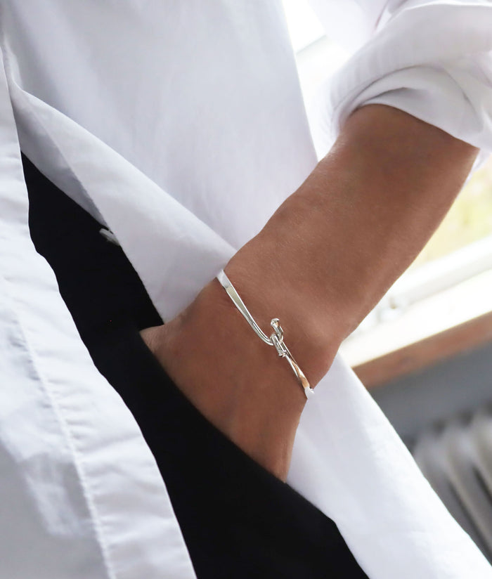 Kvinna som bär ett stelt silverarmband i äkta silver.