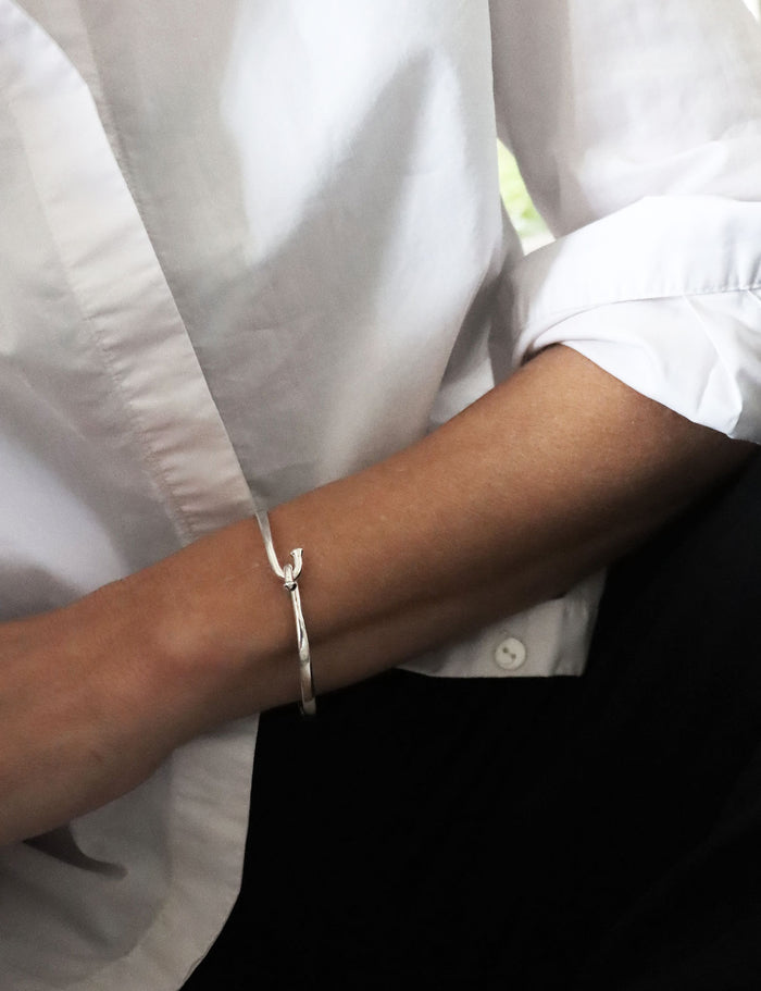 Kvinna som bär ett stelt silverarmband i äkta silver.