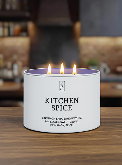 Candle labeled 'Kitchen Spice' with flames on a wooden surface.