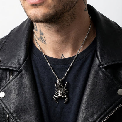 Man wearing a large silver scorpion pendant necklace on a chain with black t-shirt and leather biker jacket, featuring detailed scorpion design and neck tattoos visible