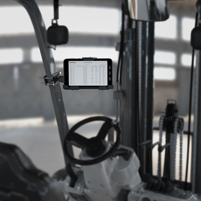 A LockVise™ Metal Locking Front Guard Tablet Mount with 8.5″ Metal Robust™ Shaft is installed inside a forklift cabin, securely holding a tablet that displays a spreadsheet on its screen, with the forklift’s controls and mechanical parts visible in the background.