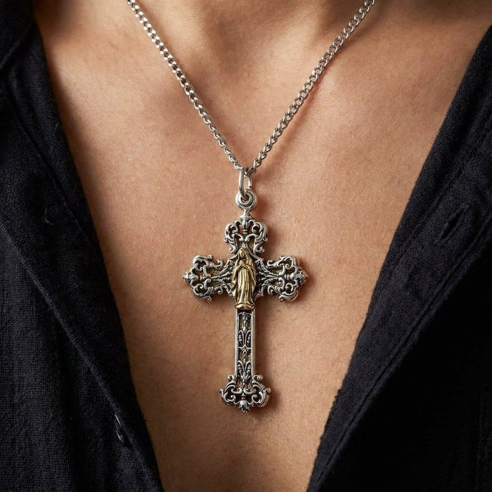Lifestyle view showing the ornate silver and brass Mary angel cross pendant worn on a chain against a black shirt.