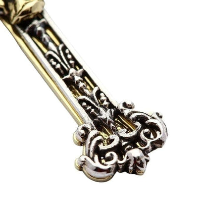 Macro view of the lower cross arm, highlighting the ornate sterling silver scrollwork layered over a smooth brass base.