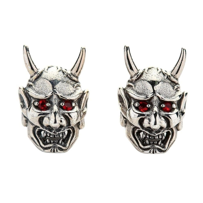 A front view of the pair of sterling silver Oni mask earrings, highlighting their fiery red CZ eyes.
