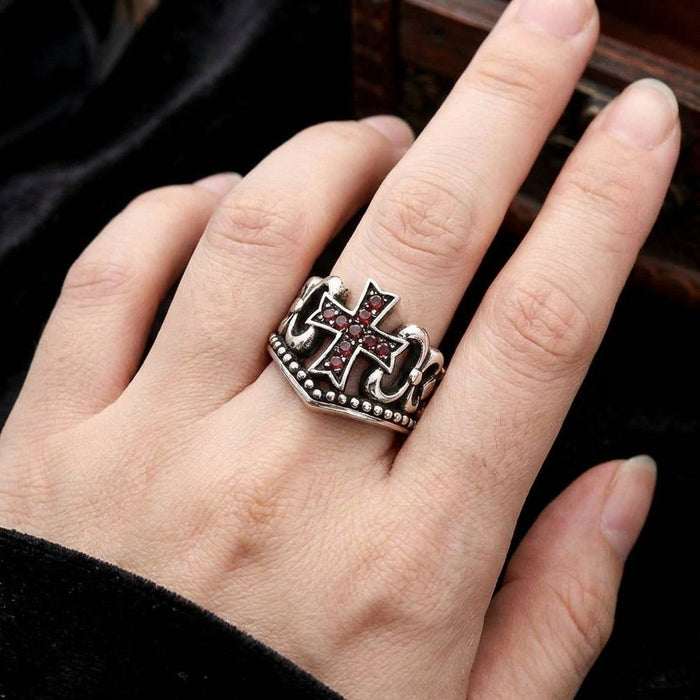 Hand wearing the oxidized sterling silver ring, showing the scale of the red garnet cubic zirconia cross and ornate band.