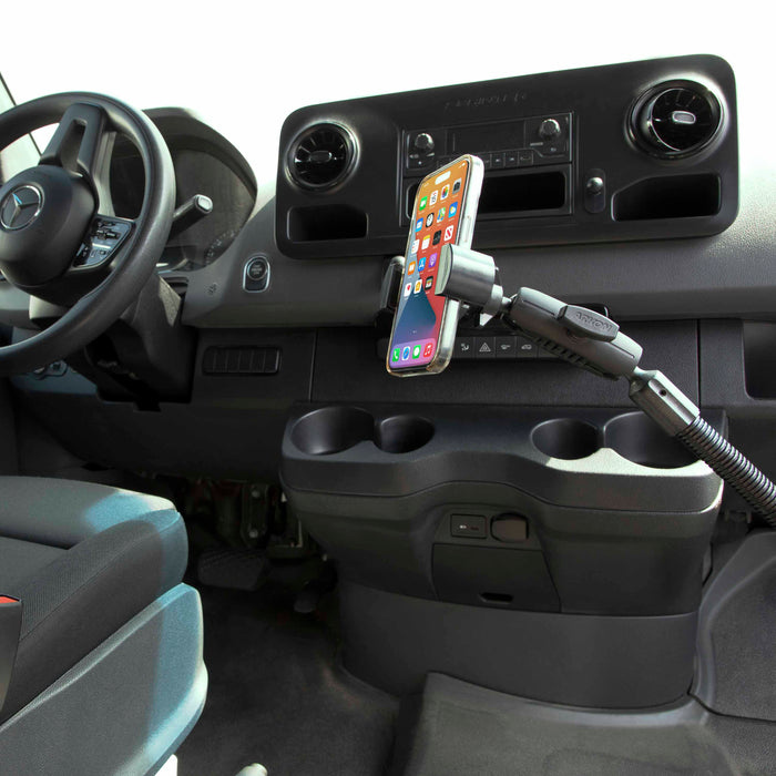 The RoadVise® Heavy-Duty Seat Rail or Floor Phone Mount holds a smartphone securely, attaching to the vehicle’s seat rail or floor near the dashboard, steering wheel, and cup holders in a modern car interior.