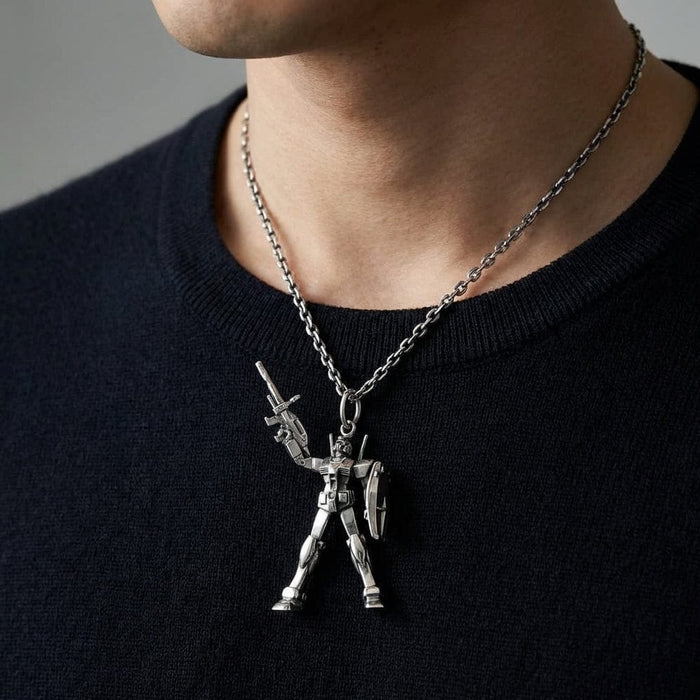 Close-up of a man wearing a detailed silver RX78-2 Gundam robot pendant on a silver chain necklace over a black crewneck sweater.