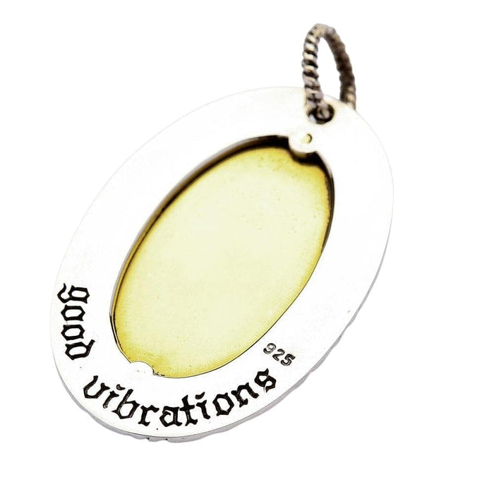 Oval inlay in pale brass sits inside oxidized engraving, under a rope-style bail stamped 925.