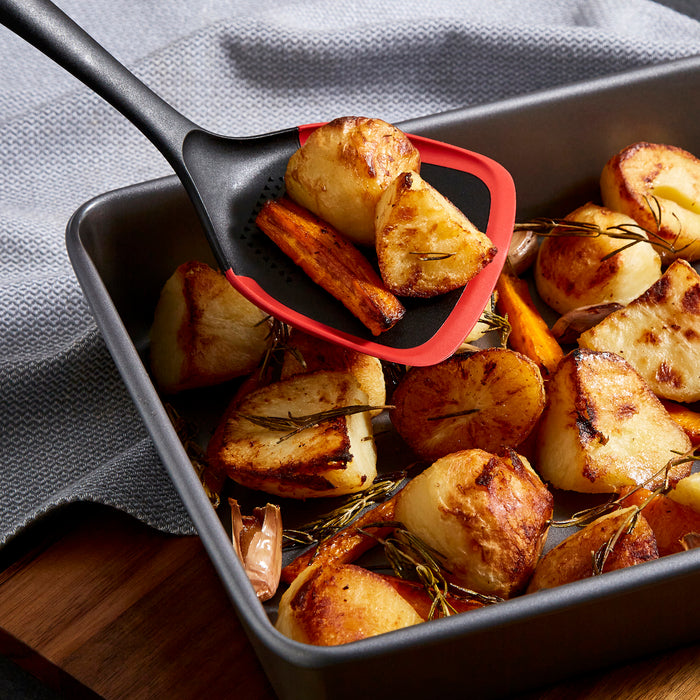 Solid turner picking up roast potatoes
