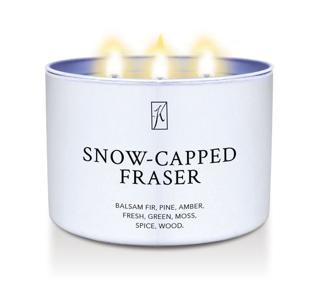 Candle in a white tin container labeled 'Snow-Capped Fraser' with flames on a white background