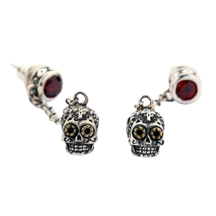 A pair of solid sterling silver dangle sugar skull earrings with brilliant red gemstone studs and golden-eyed Calavera charms.