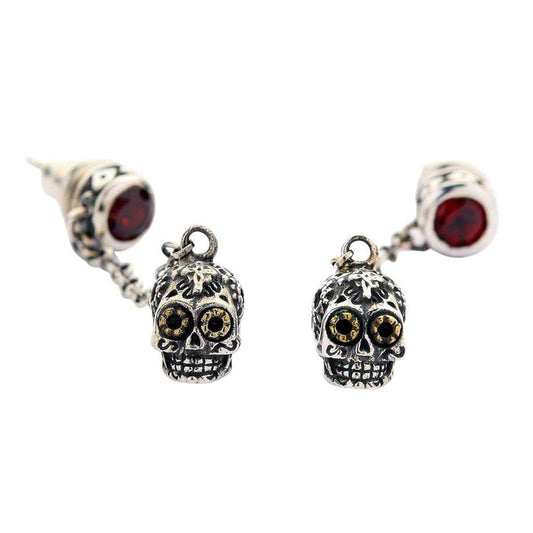 A pair of solid sterling silver dangle sugar skull earrings with brilliant red gemstone studs and golden-eyed Calavera charms.