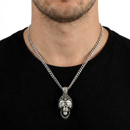 Close-up of a male model wearing a silver tribal skull pendant necklace featuring diamond-studded eyes and mouth, styled over a black t-shirt.