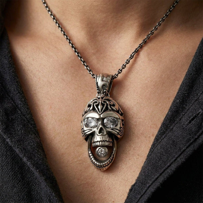 Close-up on the chest showing the silver skull's open mouth with a CZ stone, jeweled eyes, and tribal forehead engravings.