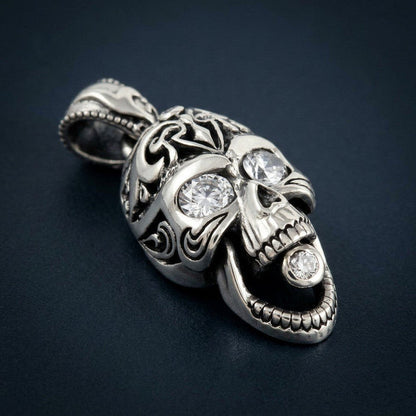 Studio shot of the resting silver skull pendant, emphasizing the clear CZ stones set in the eye sockets and open jaw.