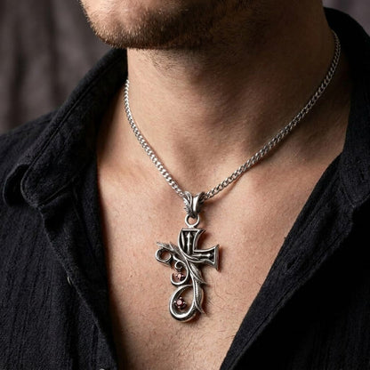 Close-up of a male model wearing an ornate silver tribal gothic cross pendant featuring two small red stones on a silver chain, styled with an open black button-down shirt.