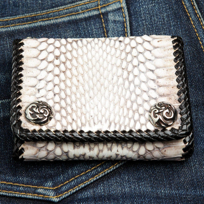 The white cobra snake biker wallet resting on a pair of dark denim jeans.