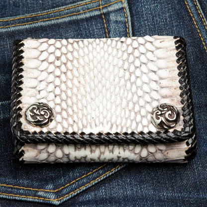 The white cobra snake biker wallet resting on a pair of dark denim jeans.