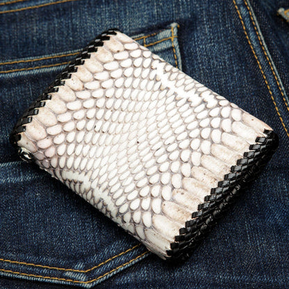White and grey cobra scales laced in black leather, a silver zipper pull at the edge on blue denim.