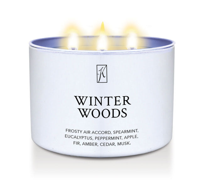 Candle in a white container labeled 'Winter Woods' with flames on a white background